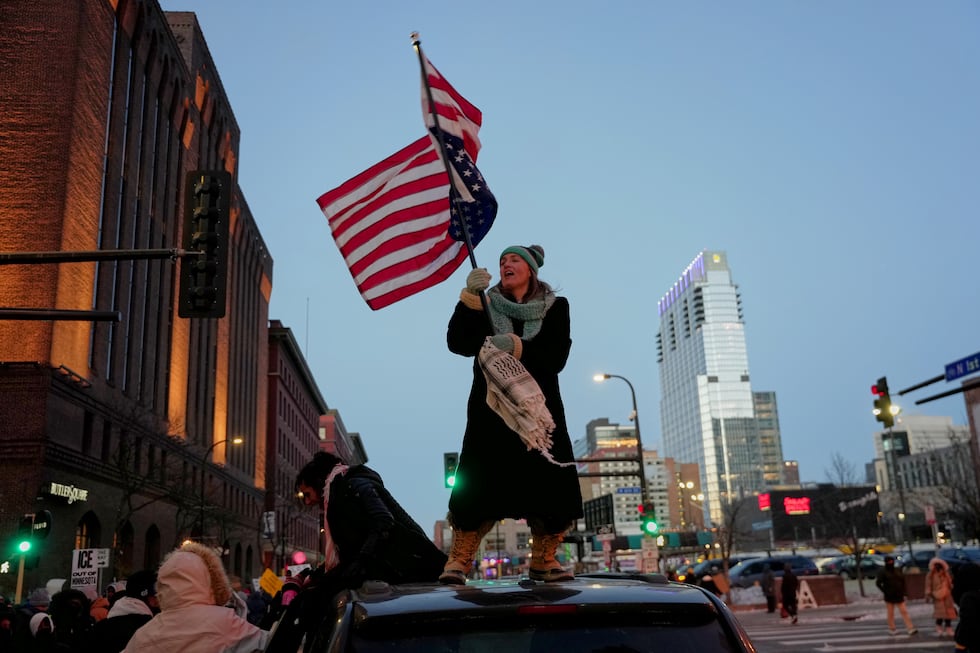 Teresa Hurst waves an upside-down American flag on top of a car during a rally against federal...