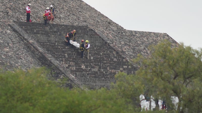 Forensic workers carry the body of a victim down a pyramid after authorities said a gunman...